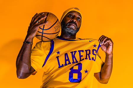 man holding his Lakers 8 jersey tank top while other hand is holding Spalding basketball on his shoulder thumbnail