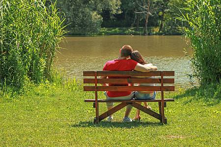man and woman sitting on bench in front body of water thumbnail
