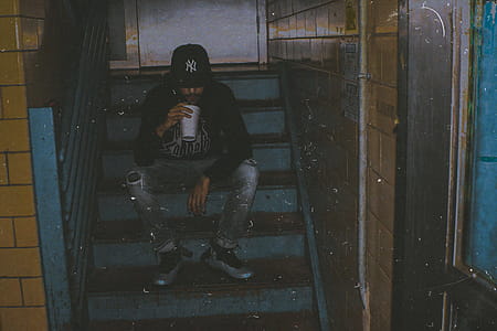 Man Holding White Cup Sitting on Stairs thumbnail