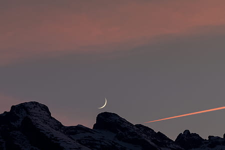 snow covered mountain under half-moon and white sky thumbnail