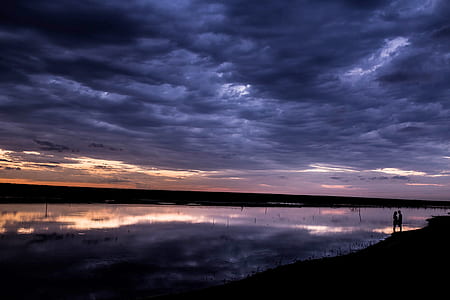 calm body of water under nimbus clouds at golden hour thumbnail