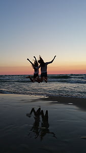 two women jumping on seashore thumbnail