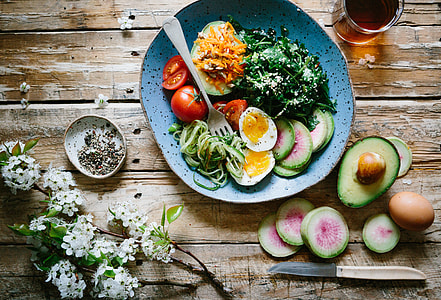 salad dish beside sliced avocado and eggs with white cherry blossoms and cup of tea thumbnail