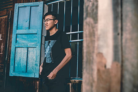woman in black crew-neck top standing in front of blue door thumbnail
