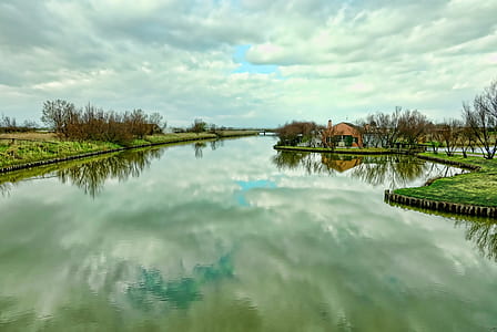 body of water near brown house under cloudy sky thumbnail