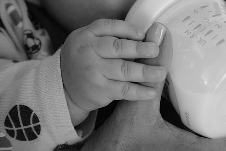 grayscale photography of baby holding feeding bottle thumbnail