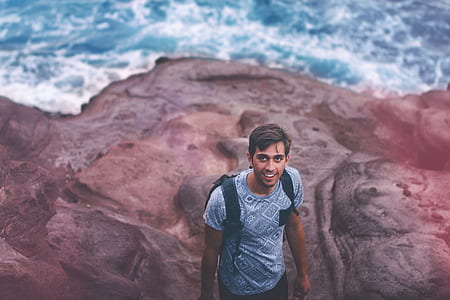 Photo Of Man Wearing Blue Shirt And Backpack Near Ocean thumbnail