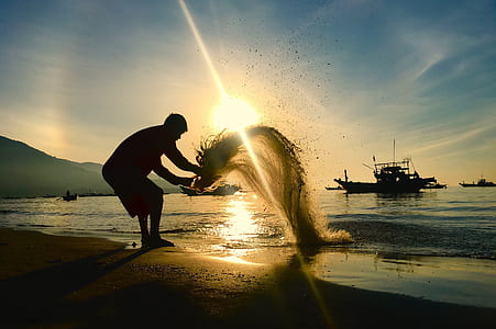 man standing at the shoreline pouring out sand thumbnail