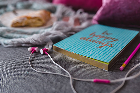 Blue notebook with a pink iPhone, headphones and a sweet bun thumbnail