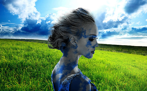 woman with blue paint on her body standing on green grass field thumbnail