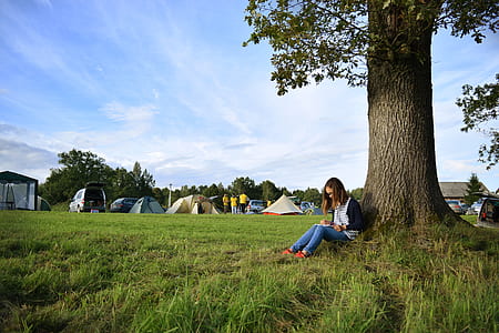 woman in blue jeans sitting beside tree thumbnail