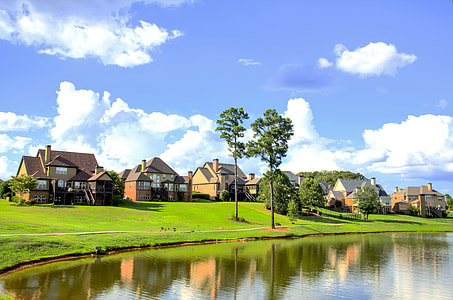 brown concrete house village near lake during daytime thumbnail