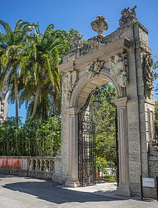 white concrete gateway near palm tree during daytime thumbnail
