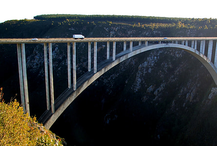 white truck passing on white concrete arch bridge at daytime thumbnail
