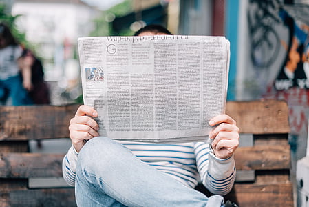 person sitting on bench while reading during daytime thumbnail