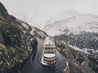 concrete building between curvy roads on mountain surrounded by snow during daytime thumbnail