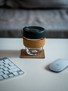 glass jar between Apple Magic Mouse and Keyboard on white wooden surface thumbnail