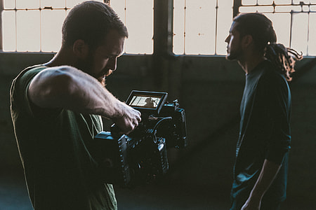 man holding black video camera while filming man in front thumbnail