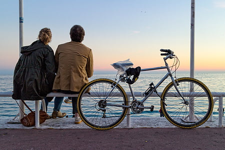 man and woman sitting on bench near bicycle thumbnail