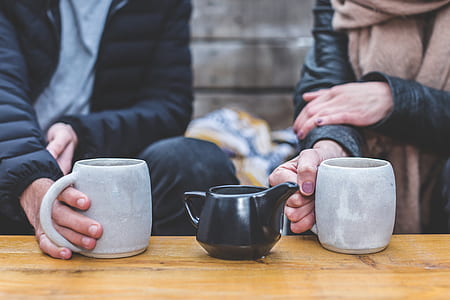 two gray ceramic mugs and black ceramic teapot on brown wooden thumbnail
