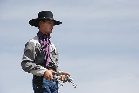 photo of man holding two gray revolvers thumbnail
