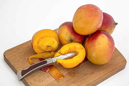 sliced mango beside four mangoes on chopping board thumbnail