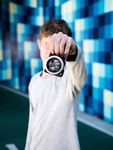 man holding a black digital camera inside blue room thumbnail