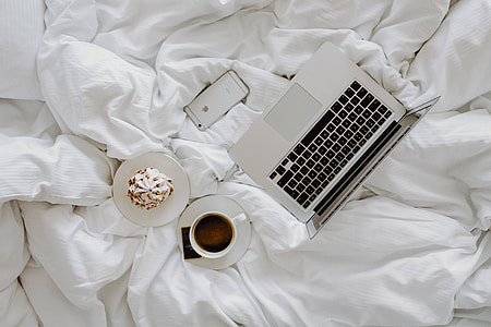 Woman working on a laptop while enjoying a breakfast coffee and chocolate in bed thumbnail