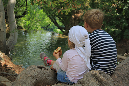 photography of boy and girl sitting on rock thumbnail
