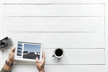 Person Using Tablet Computer Near Mug and Camera thumbnail