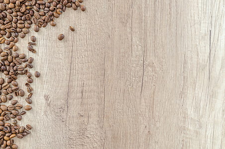 roasted brown coffee beans scattered on brown wooden surface thumbnail