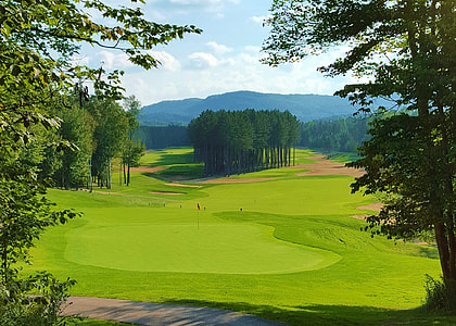 landscape photo of green golf field under cloudy sky during daytime thumbnail
