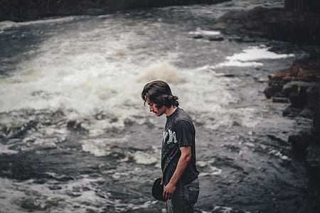 man standing near rushing river at daytime thumbnail
