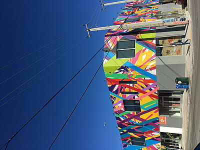 person walking alone on sidewalk near colorful building thumbnail
