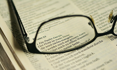 selective focus photography of eyeglasses on top of Bible thumbnail