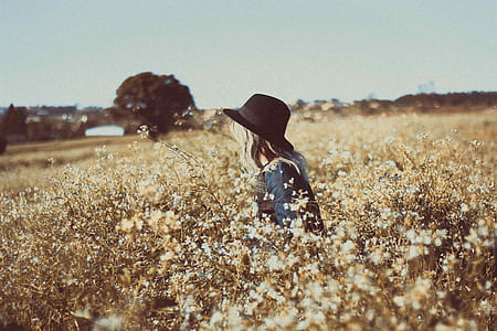 person in grey top with black hat sitting on brown field thumbnail