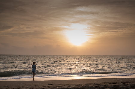 woman walking on shoreline during golden hour thumbnail