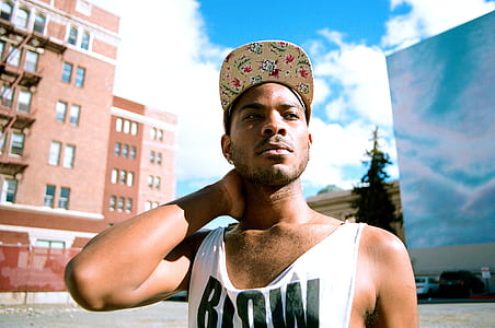 man standing wearing white tank top under blue cloudy sky thumbnail