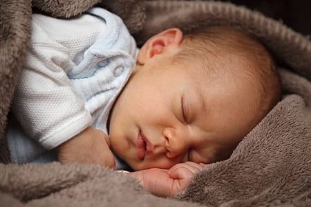 baby wearing white long-sleeved shirt sleeping on brown fleece sleep sack thumbnail