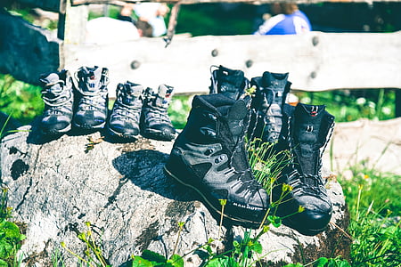 four pairs of black hiking shoes on gray rock thumbnail