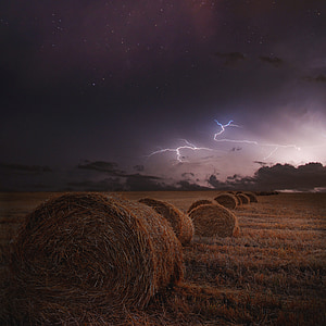 pile of rolled haystack under lightning and clouds thumbnail