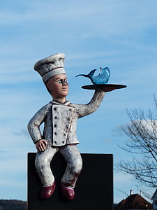 chef holding tray with blue fish statue thumbnail