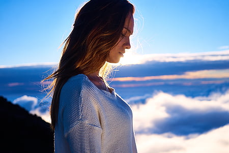 woman in white top standing near clouds on top of mountain thumbnail