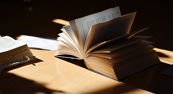 two books on brown wooden surface thumbnail