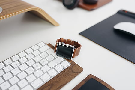 silver aluminum case Apple Watch with brown Sport Band near Apple Magic Keyboard thumbnail