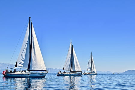 three blue sailboats in body of water thumbnail