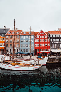 photo of two white boat near the five assorted-color 5-storey buldings thumbnail