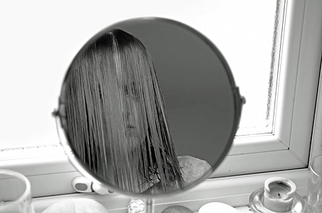 woman looking on mirror near window thumbnail