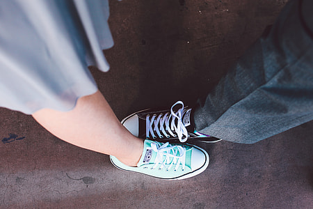 close up photo of man and woman in teal and black Converse All Star low top sneakers thumbnail