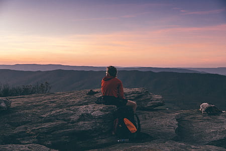 person sitting on gray stone at sunset thumbnail